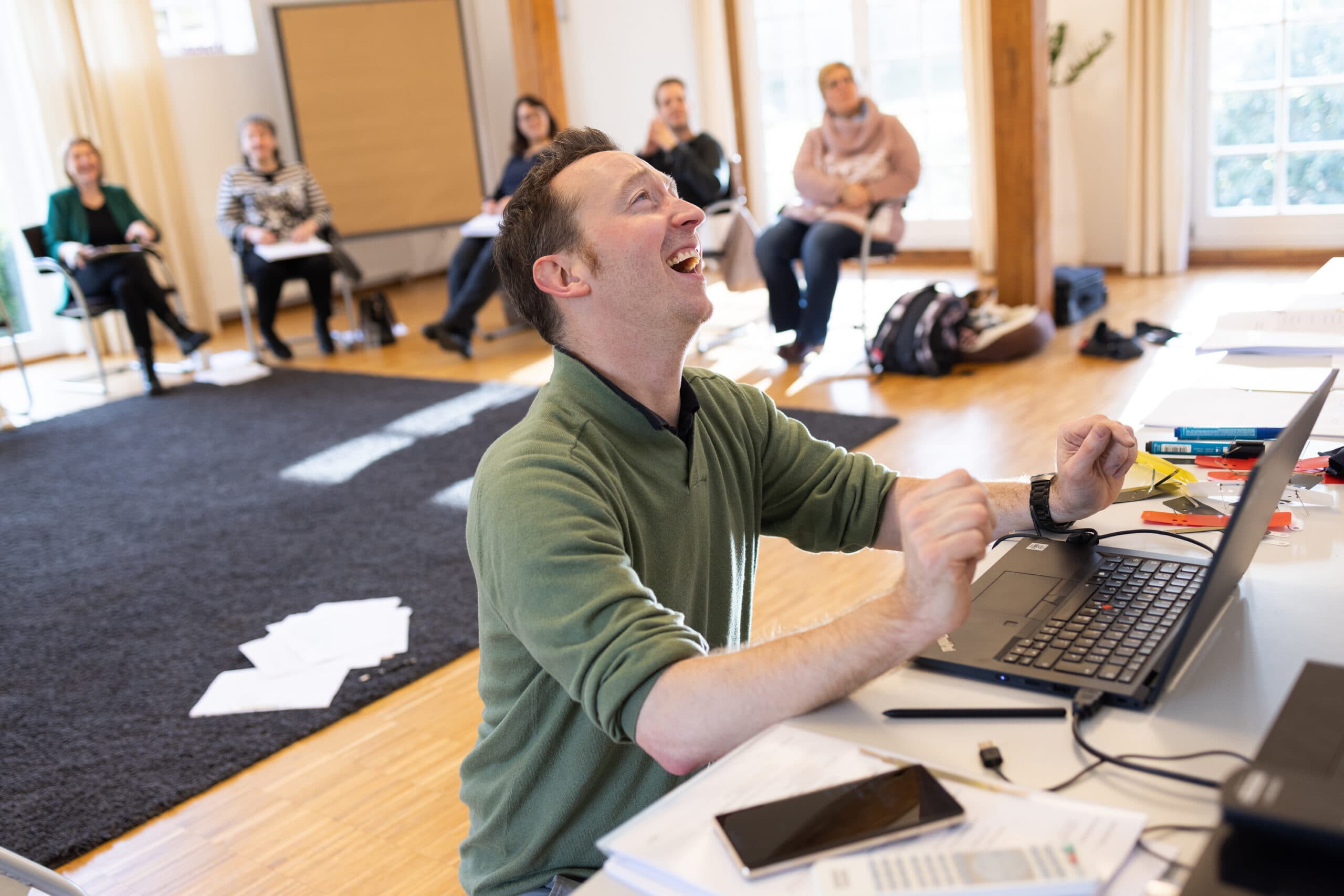 Geschäftsführer Jan Siebenmark freut sich in einem Workshop vor dem Laptop